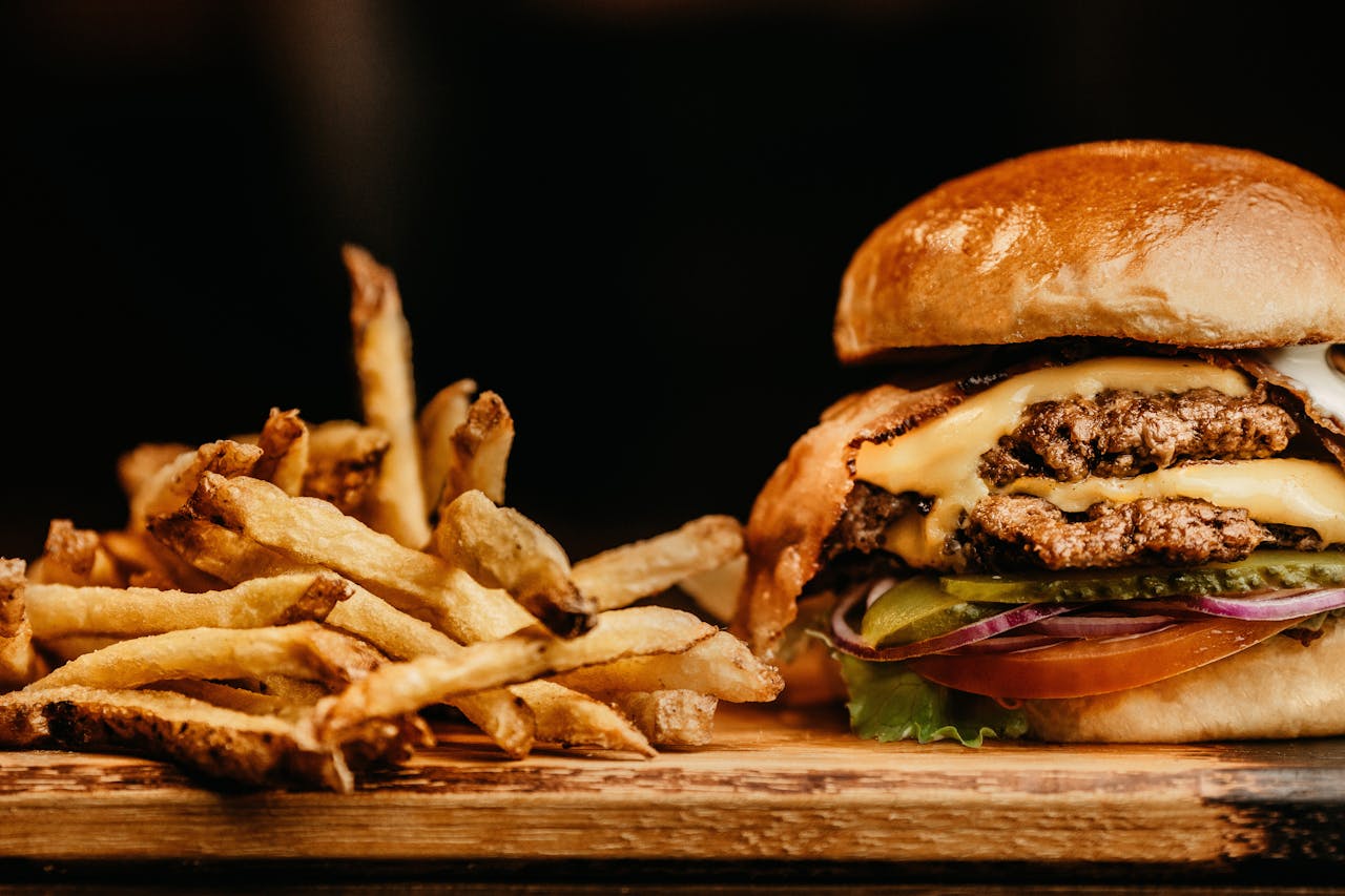Mouthwatering cheeseburger and crispy fries on a wooden board, perfectly capturing fast food appeal.